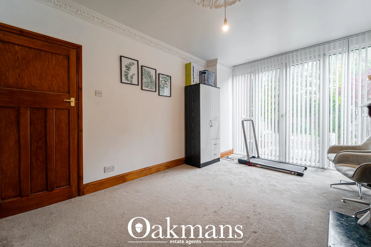 Bright living room with cream carpet, white vertical blinds, wooden wall panelling, framed botanical prints, wardrobe st