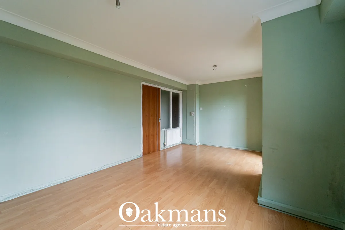 Spacious living room with sage green walls, white ceiling, wooden flooring, patio doors and radiator