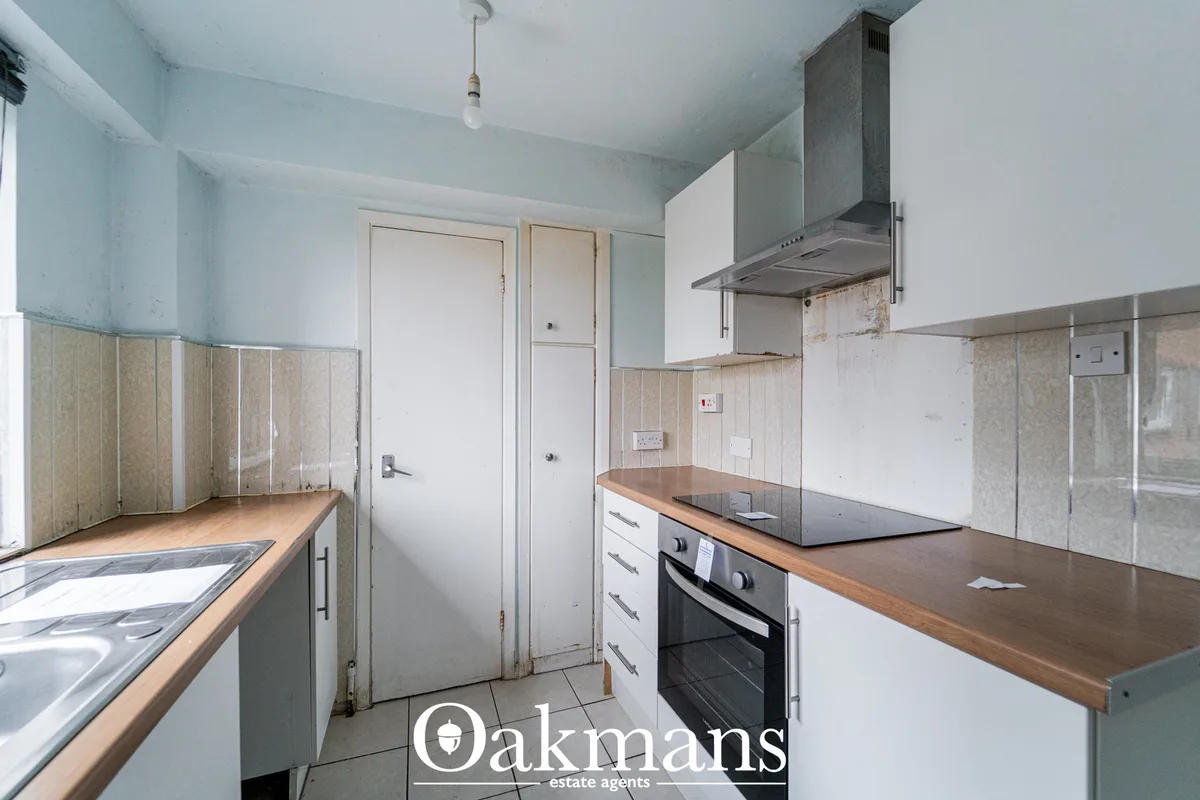 Galley kitchen with wooden worktops, white units, black oven, stainless steel extractor hood and tiled splashback