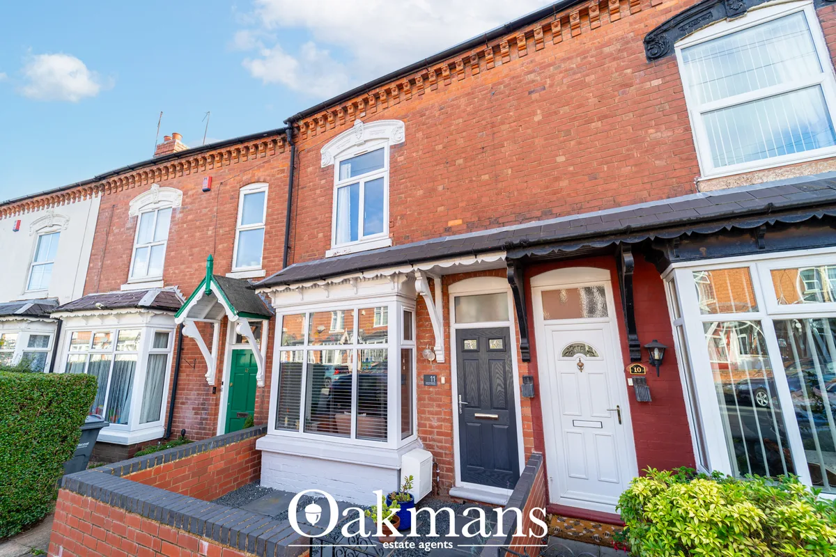 Red brick terraced houses with white window frames, front gardens and varied door colours including green, black and red