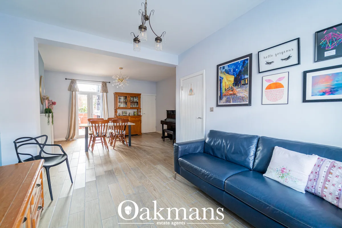 Bright living room with blue leather sofa, framed artwork on walls, wooden flooring, pendant lighting and open-plan acce