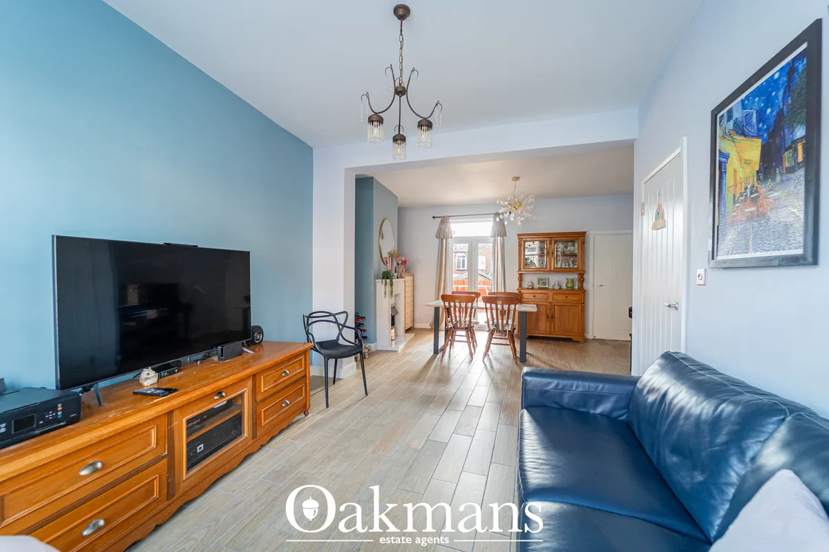 Open-plan living and dining area with blue feature wall, wooden TV unit, leather sofa, pendant lights and wooden furnitu