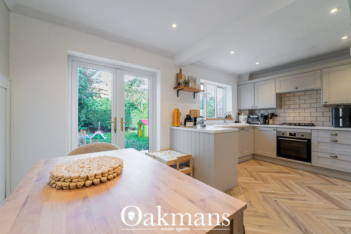 Modern kitchen with white cabinetry, subway tile backsplash, wooden worktops, integrated oven, and French doors opening 