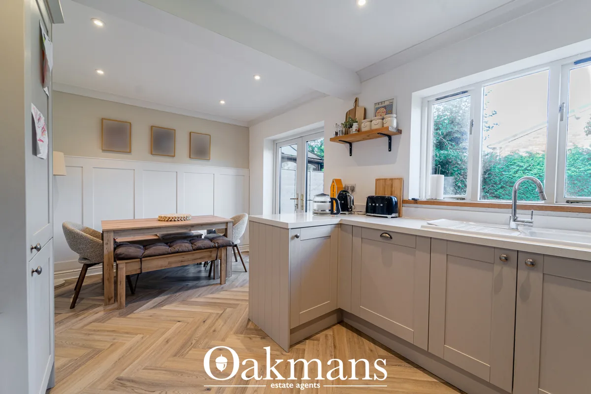 Modern fitted kitchen with taupe cabinetry, white worktops, integrated appliances and breakfast bar. Wooden herringbone 