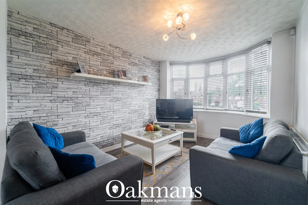 Modern living room with grey sofas, blue cushions, grey brick feature wall, white floating shelf, TV unit, coffee table 