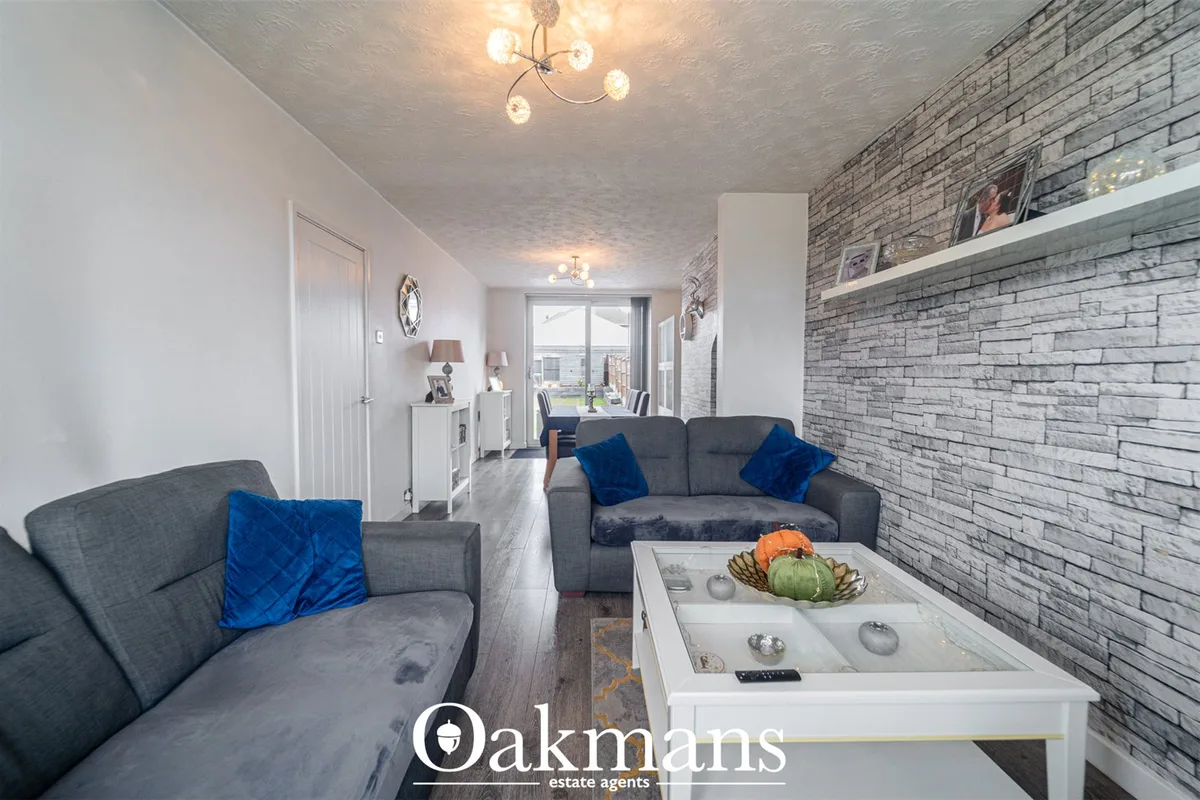 Contemporary living room with grey upholstered seating, blue velvet cushions, exposed brick feature wall, white display 