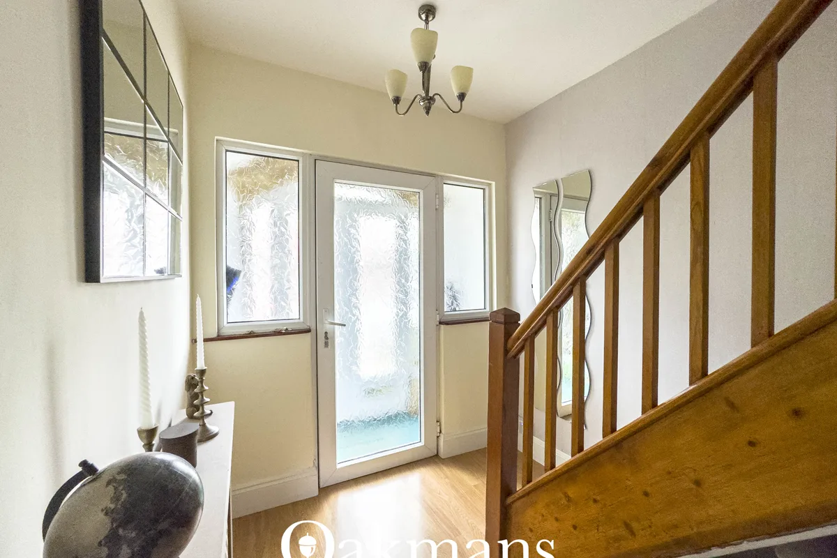 Bright hallway with wooden staircase, multiple windows with frosted glass, wooden flooring, cream walls and pendant ligh