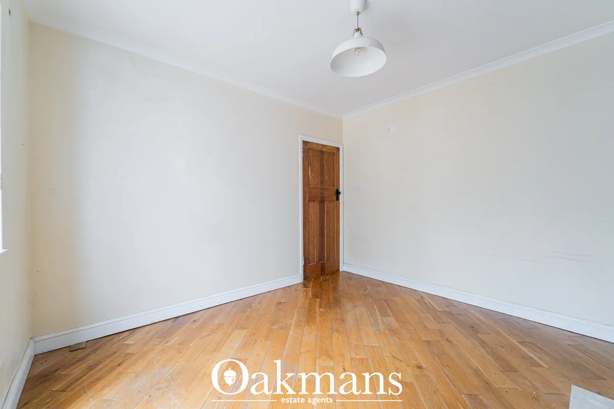 Bright hallway with wooden hardwood flooring, white walls, white ceiling with pendant light, and wooden door