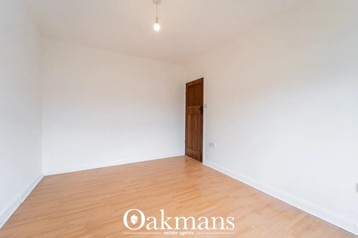 Empty hallway with wooden flooring, white walls, brown wooden door and pendant light fixture