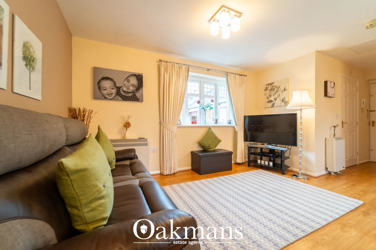 Bright living room with yellow walls, brown leather sofa with green cushions, flat-screen TV, wooden flooring and cream 