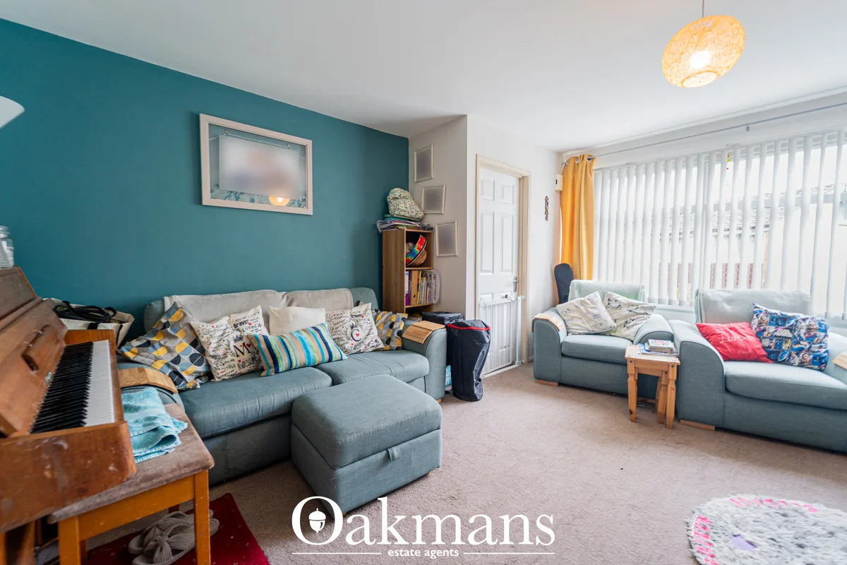 Spacious living room with teal feature wall, grey sofas, piano, woven ceiling light, and yellow curtains overlooking gar