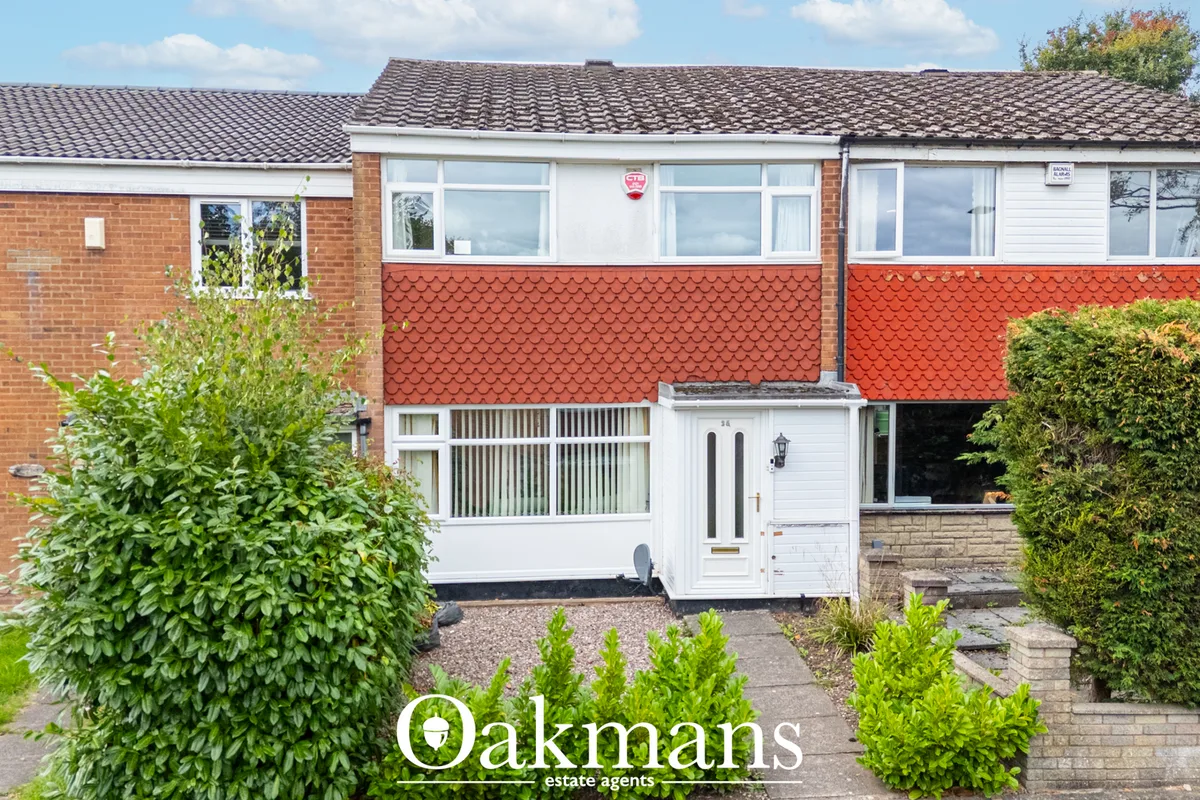 Brick and render terraced house with white-framed windows, red tiled roof, white entrance door and mature hedging to fro