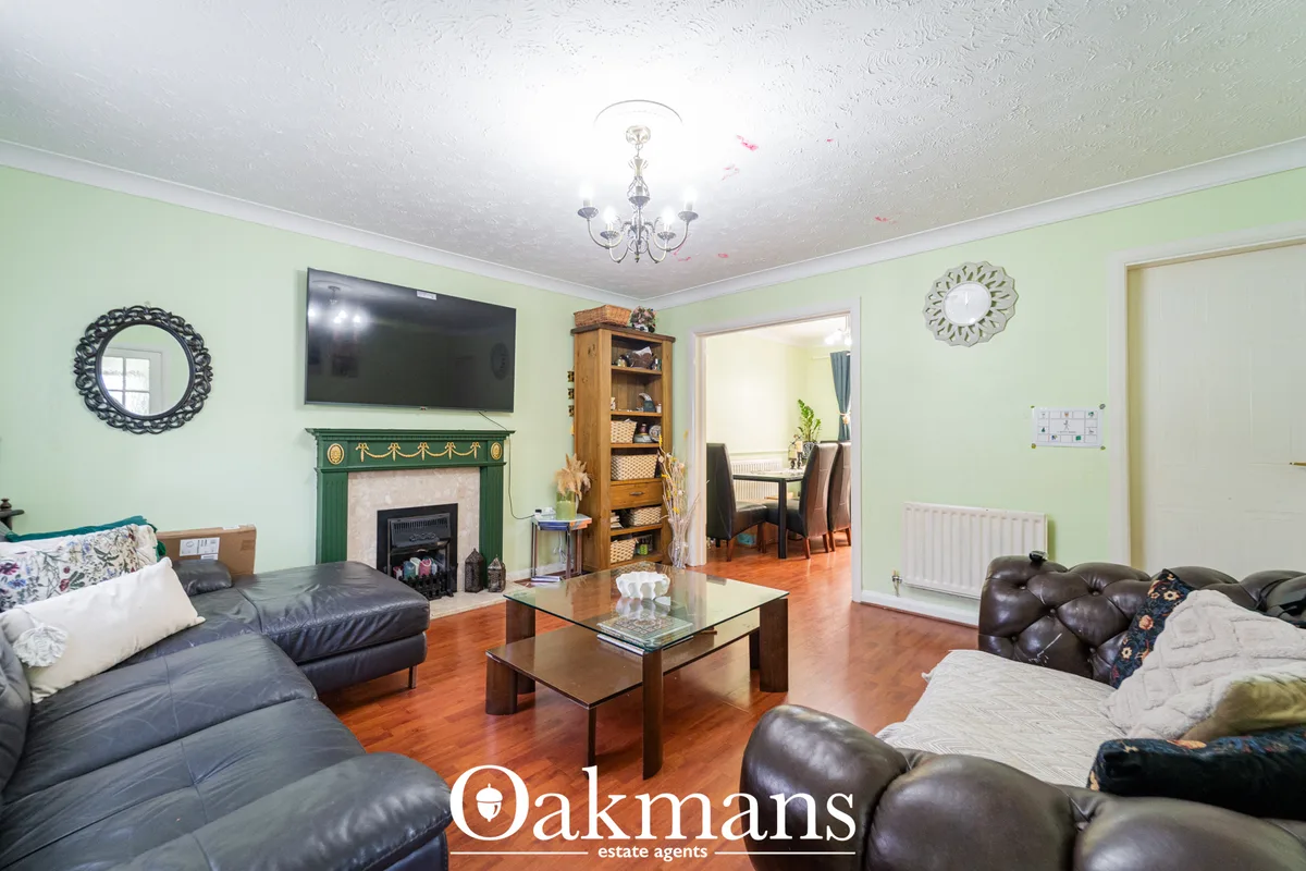 Spacious living room with pale green walls, dark leather sofas, fireplace with green surround, wall-mounted TV, wooden c