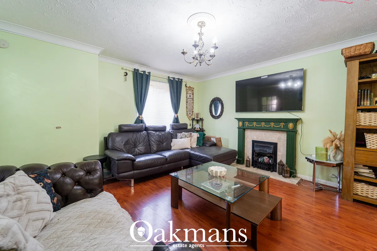 Spacious living room with pale green walls, dark leather sofa, fireplace with green surround, wall-mounted TV, wooden fl