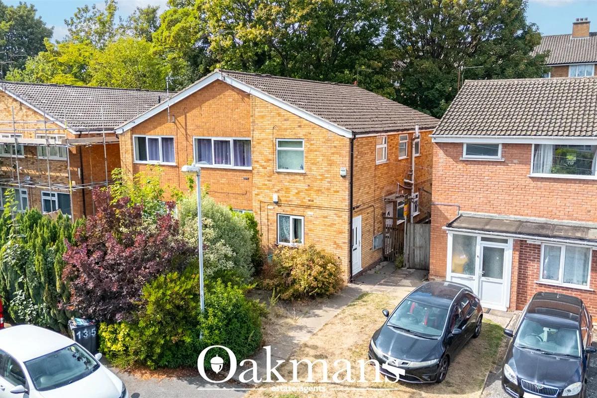 Aerial view of brick-built residential properties with driveways, parked cars, mature trees and landscaped gardens