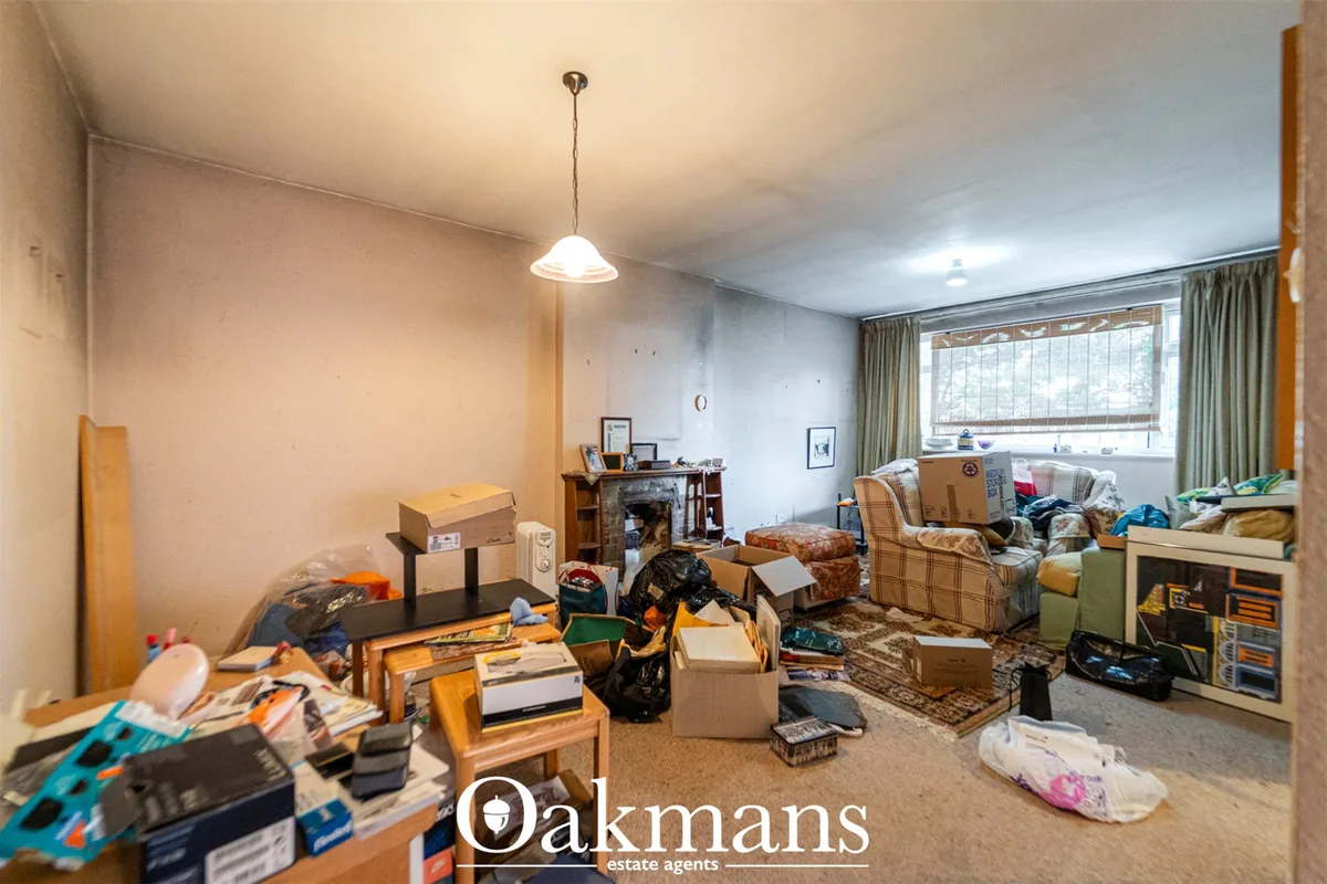 Cluttered living room with fireplace, furniture, cardboard boxes, clothing and personal items scattered throughout, larg