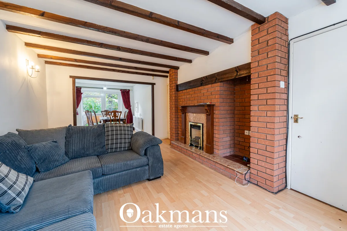 Living room with exposed wooden beams, blue striped sofa, brick fireplace with inset wood burner, wooden flooring and do