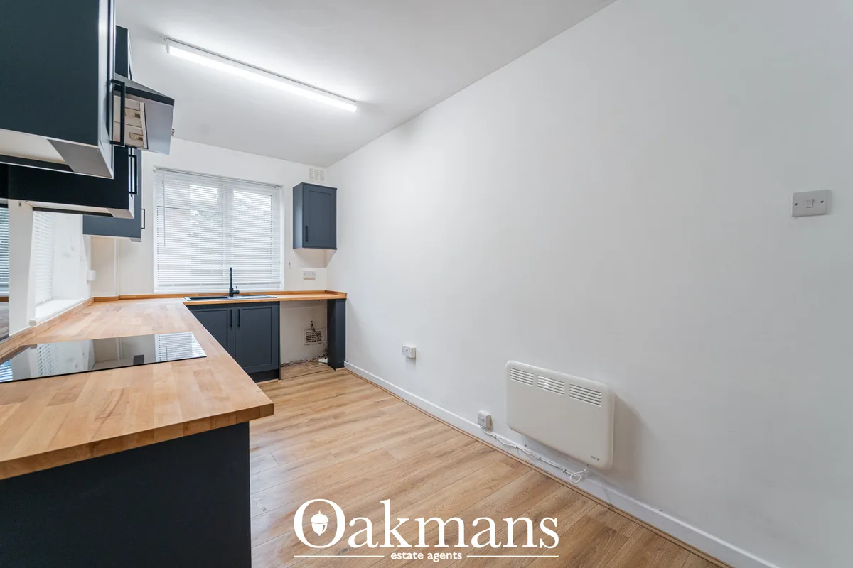 Modern kitchen with dark cabinetry, wooden worktops, fitted appliances, breakfast bar and window to rear