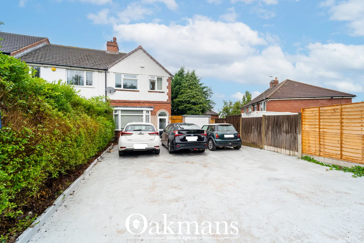 Semi-detached house with driveway parking three cars, white render and brick frontage, hedged border, wooden fencing, ne