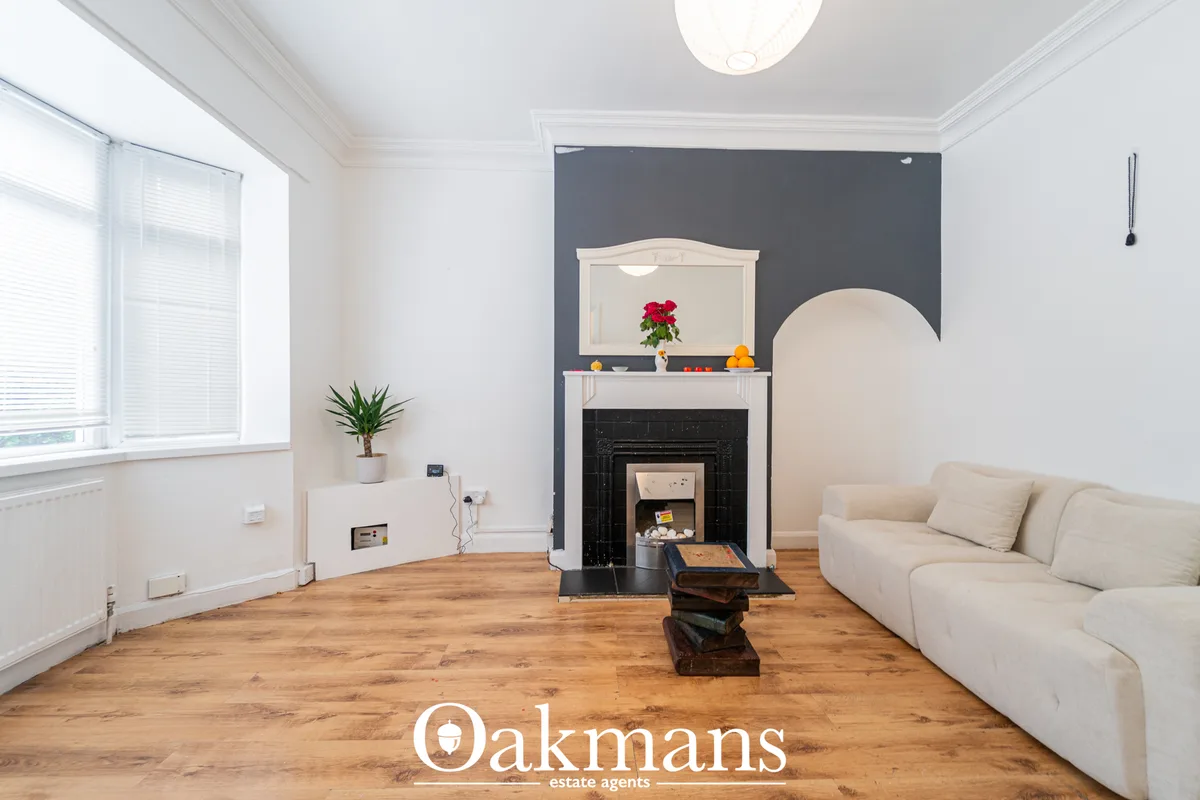 Bright living room with cream sofa, wooden flooring, fireplace with dark surround and white mantelpiece, feature wall be