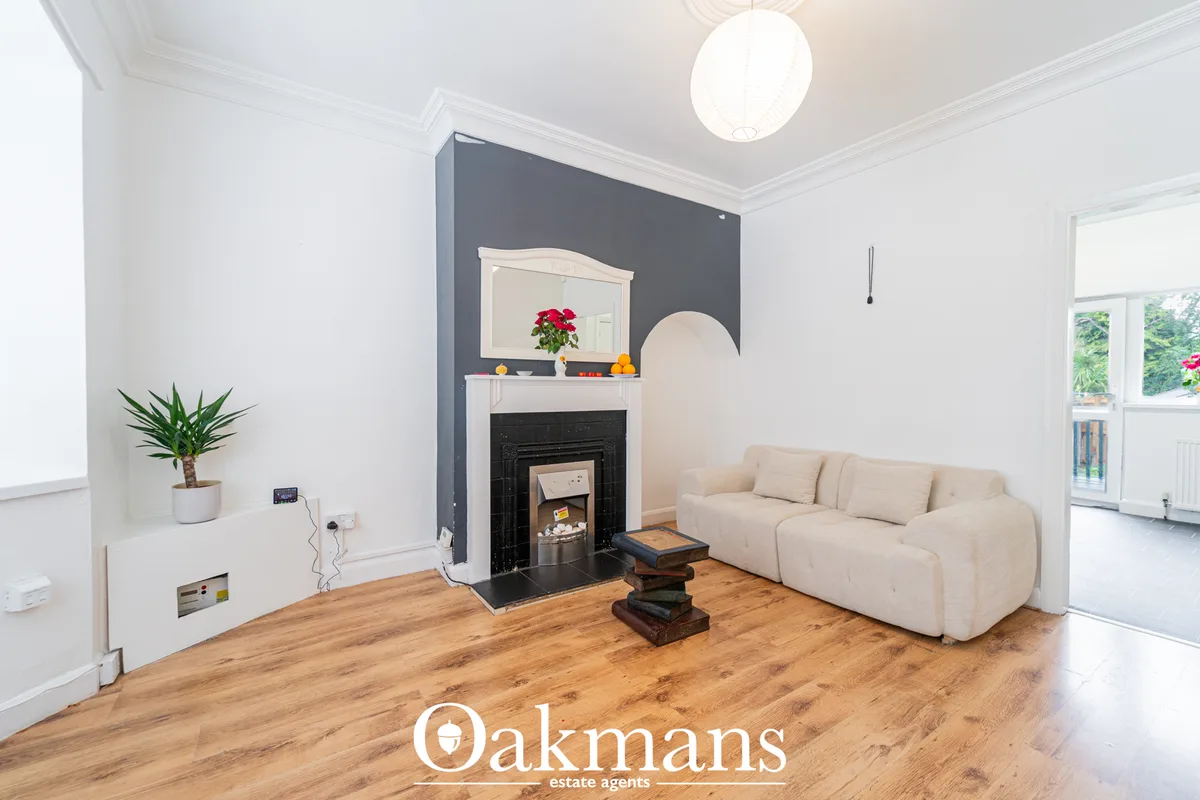 Bright living room with cream sofa, black fireplace with white mantelpiece, dark feature wall, wooden flooring and potte