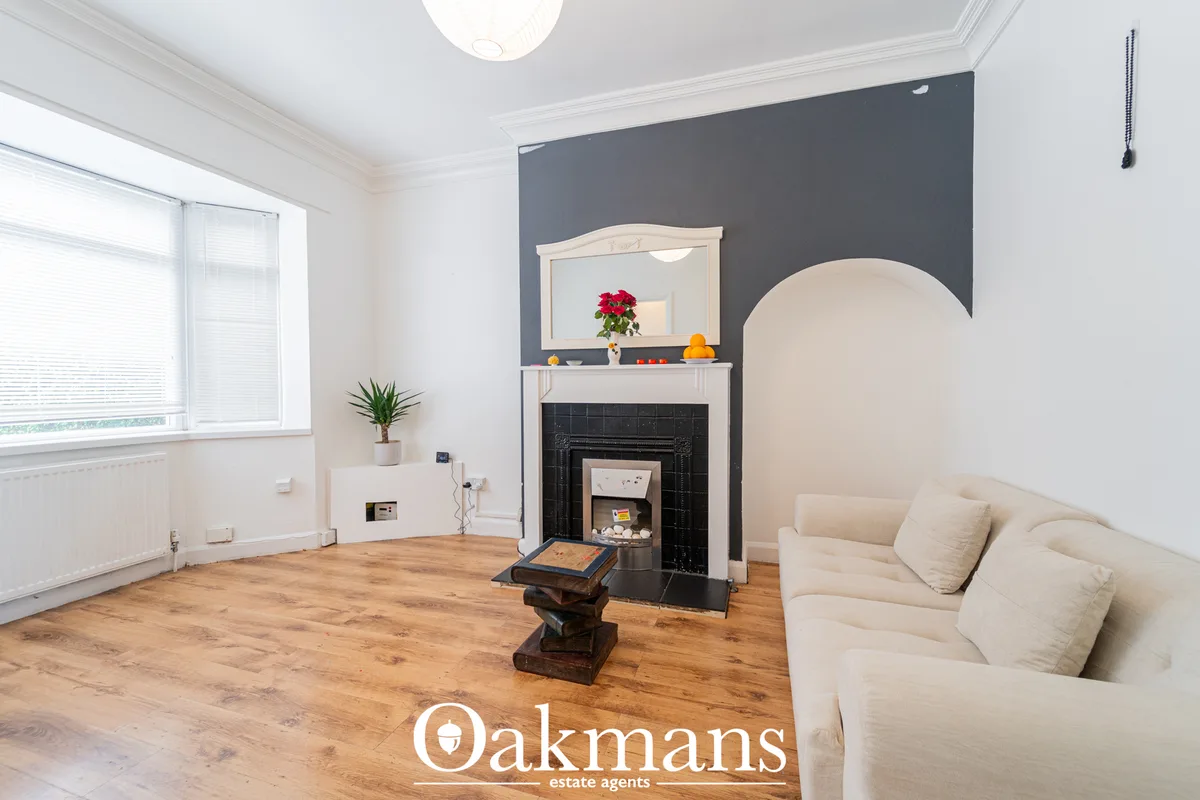 Bright living room with cream sofa, fireplace with black surround and white mantelpiece, feature wall, wooden floor and 