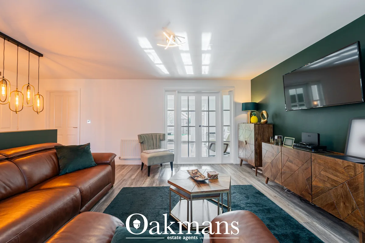 Contemporary living room with cognac leather sofa, teal accent chair, wooden coffee table, glazed patio doors, green fea