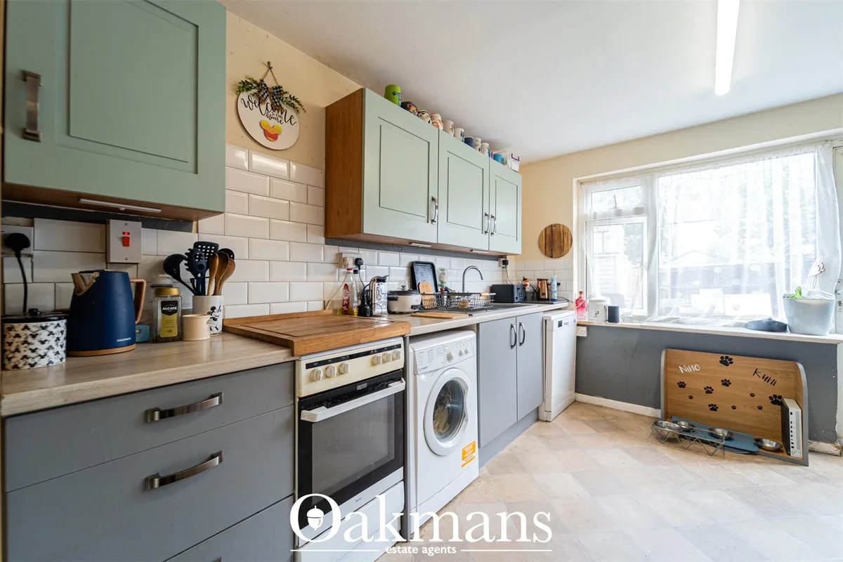 Modern fitted kitchen with grey and white cabinetry, wooden worktops, integrated appliances, subway tile splashback and 