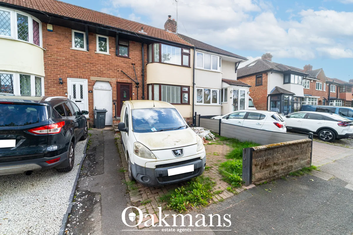 Brick semi-detached house with white and cream render, parked cars on driveway, brick boundary wall, neighbouring proper