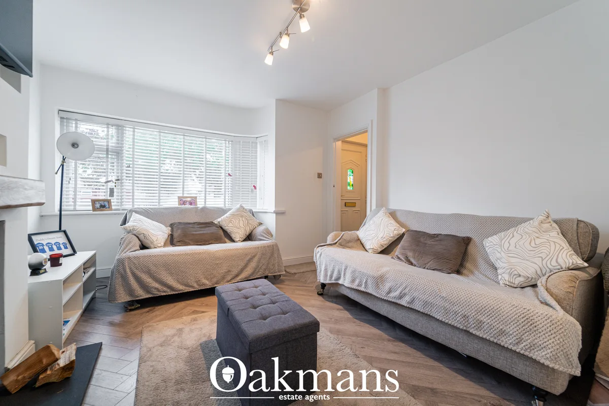 Bright living room with two beige sofas, bay windows with shutters, wooden flooring, modern track lighting and neutral d