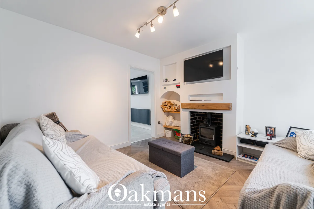 Bright living room with twin sofas, fireplace with wooden mantel, wall-mounted TV, wood flooring and recessed lighting