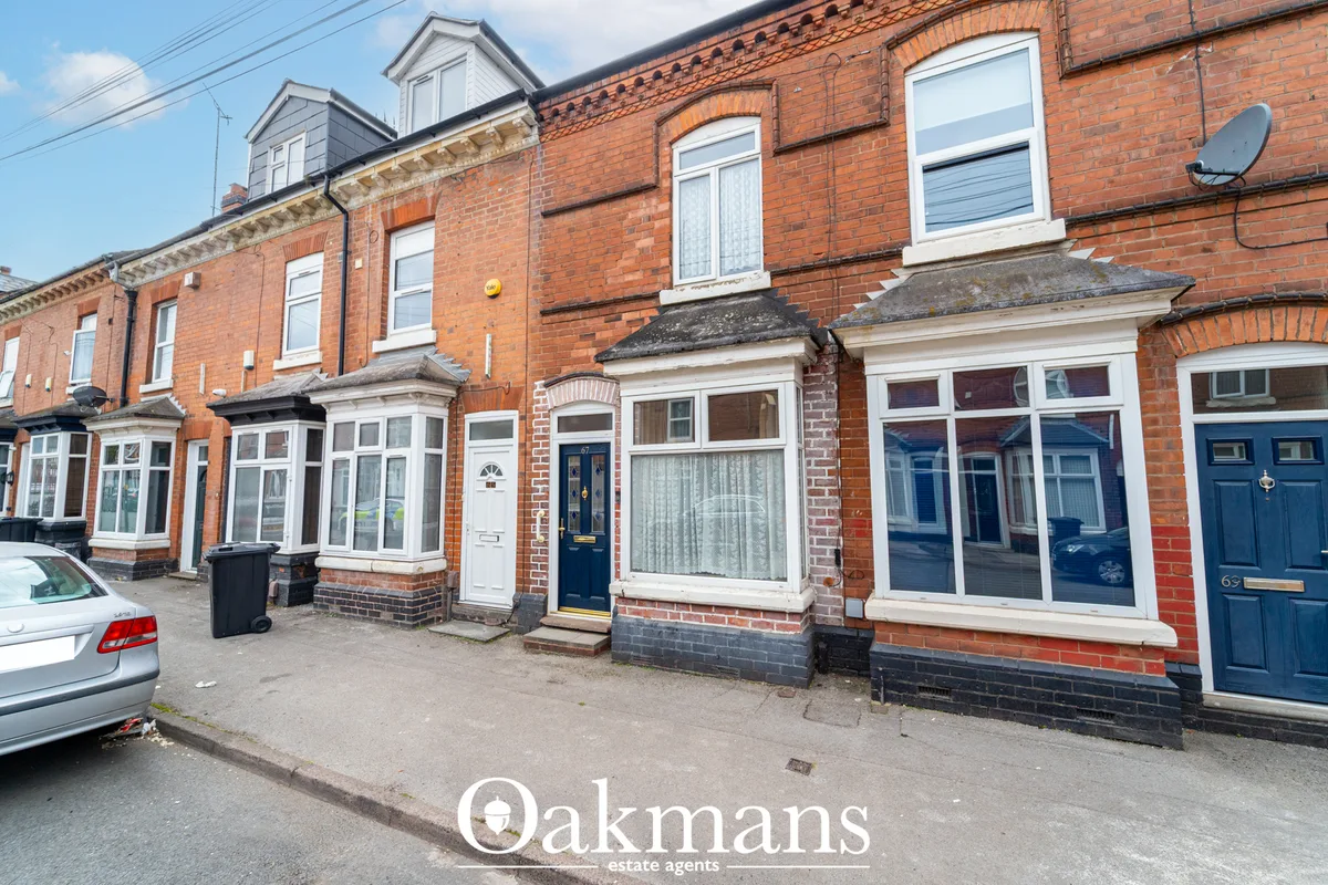 Row of Victorian red brick terraced houses with white-framed windows, blue doors and dormer windows, viewed from street 