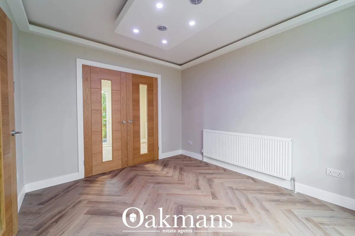 Spacious entrance hallway with herringbone wood flooring, recessed ceiling lights, white radiator, pale lavender walls a
