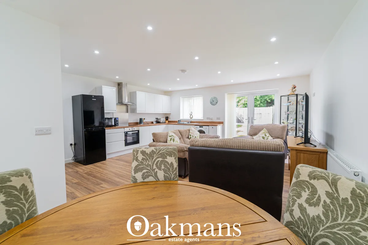 Open-plan living area with striped sofa, black leather armchair, round wooden dining table with patterned chairs, and in