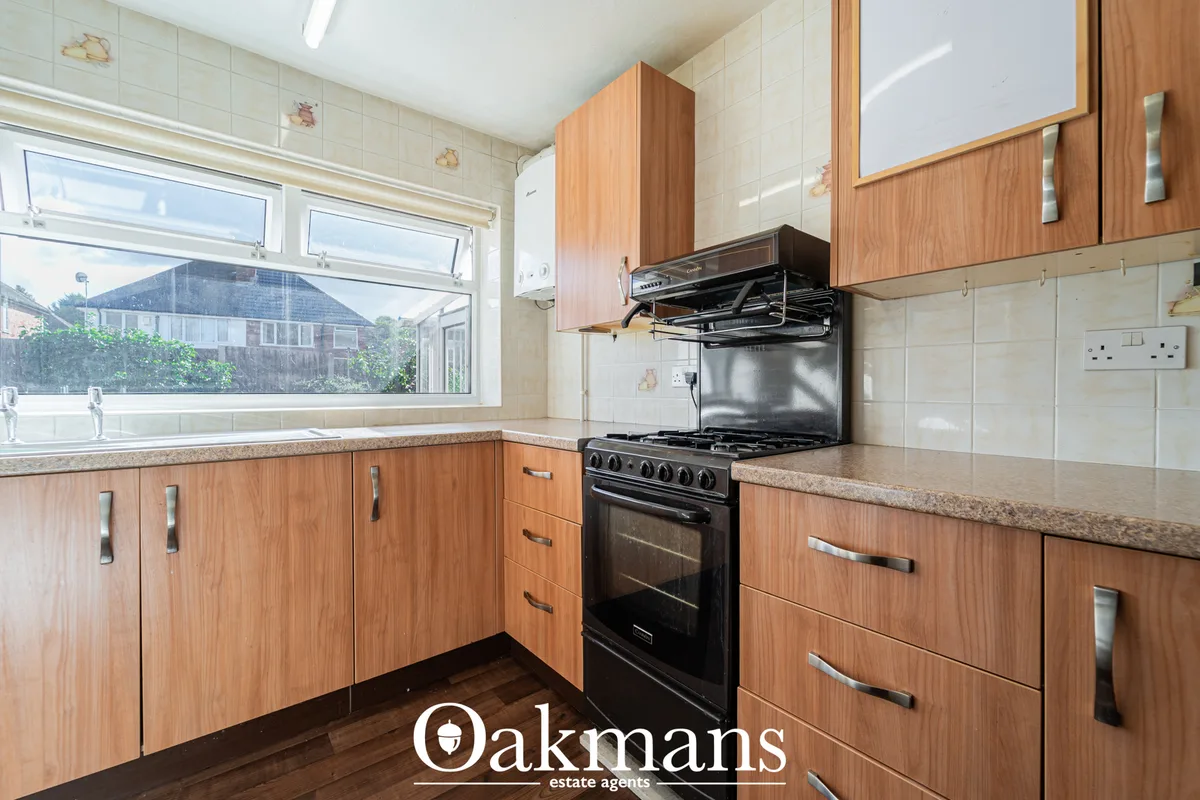 Modern fitted kitchen with wooden cabinetry, granite worktops, black range cooker, and large window overlooking garden