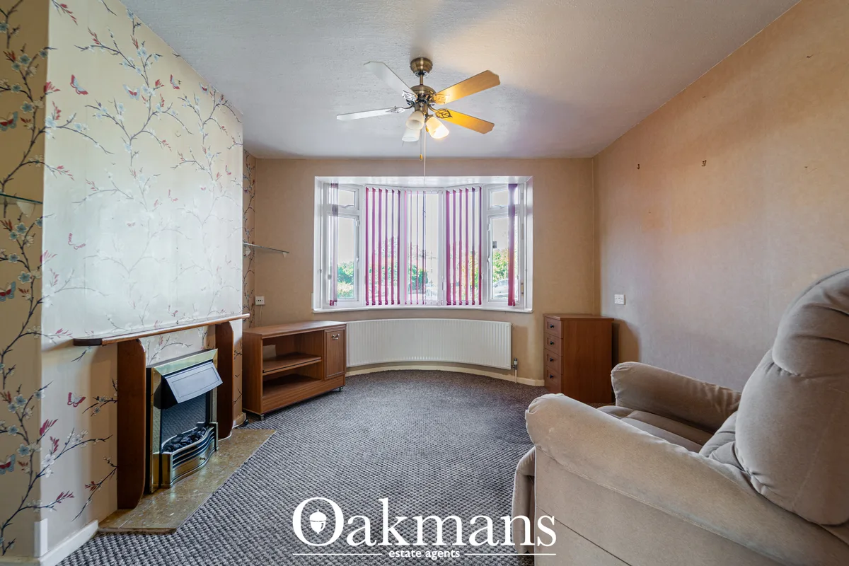 Spacious living room with bay window, cream upholstered sofas, wooden furniture, floral wallpaper, ceiling fan and purpl