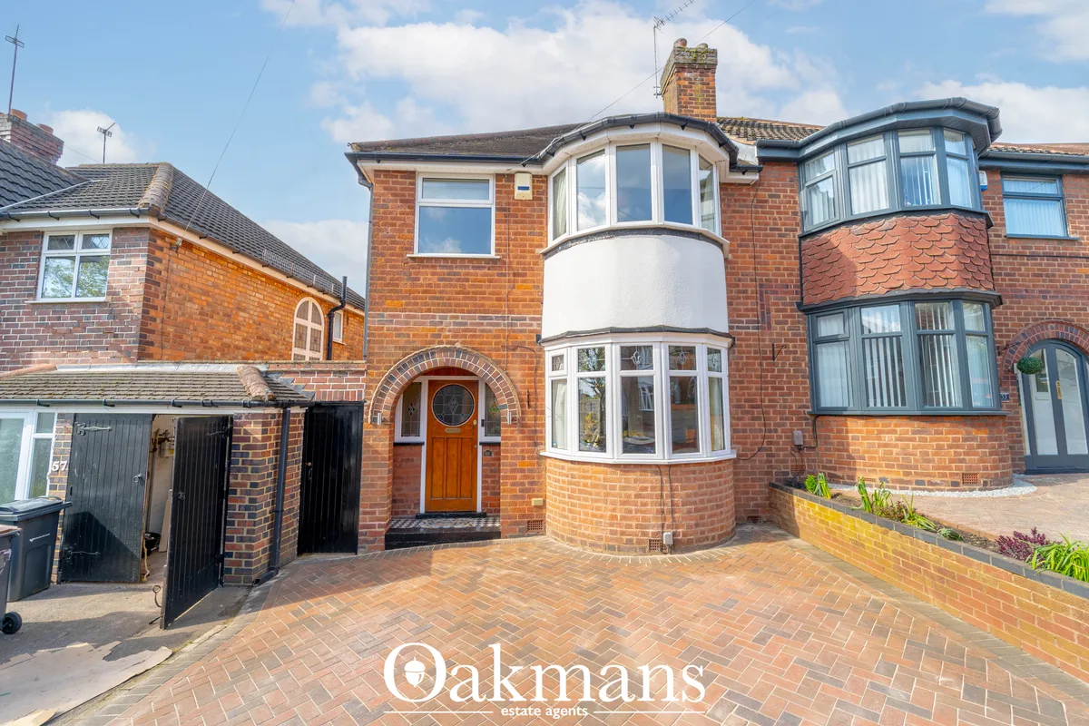 Red brick semi-detached house with bay windows, white-framed glazing, wooden entrance door, herringbone driveway and man