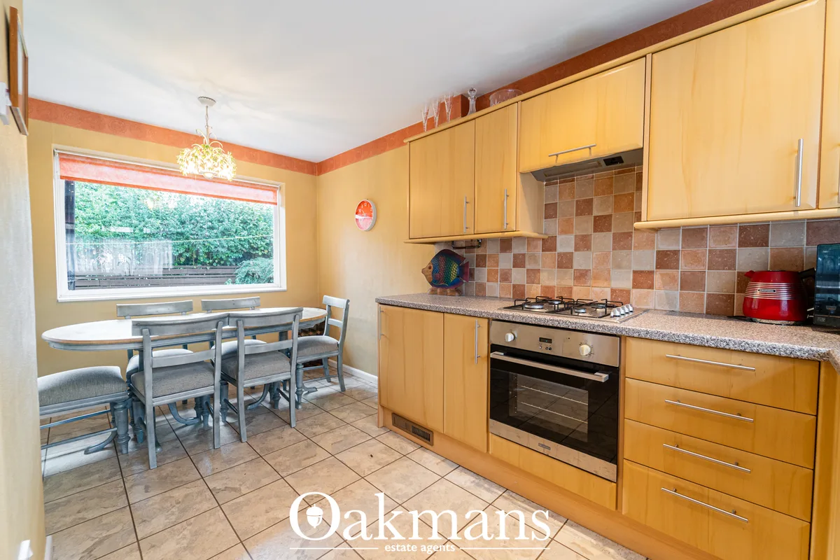 Bright kitchen with pine-effect units, terracotta checkerboard splashback, stainless steel appliances and dining area wi