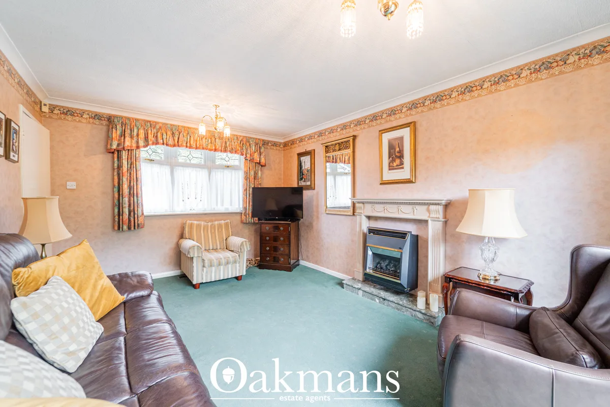 Spacious living room with brown leather sofas, fireplace with white mantelpiece, striped accent chair, sage-green carpet