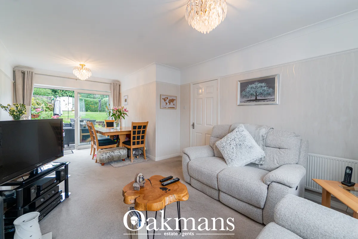 Bright open-plan living room with grey upholstered sofa, wooden coffee table, TV unit, dining area with wooden table and
