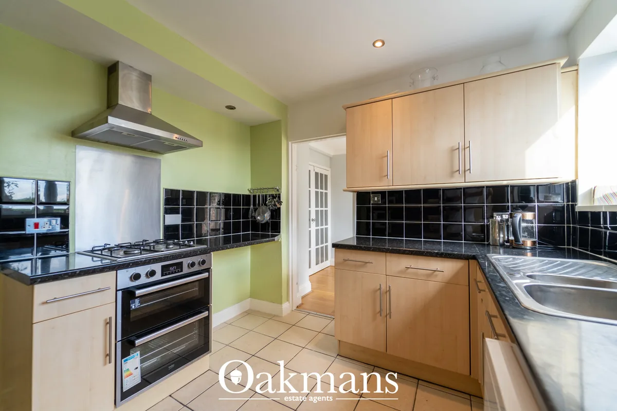 Modern fitted kitchen with lime green walls, wooden units, black granite worktops, double oven, gas hob and black metro 