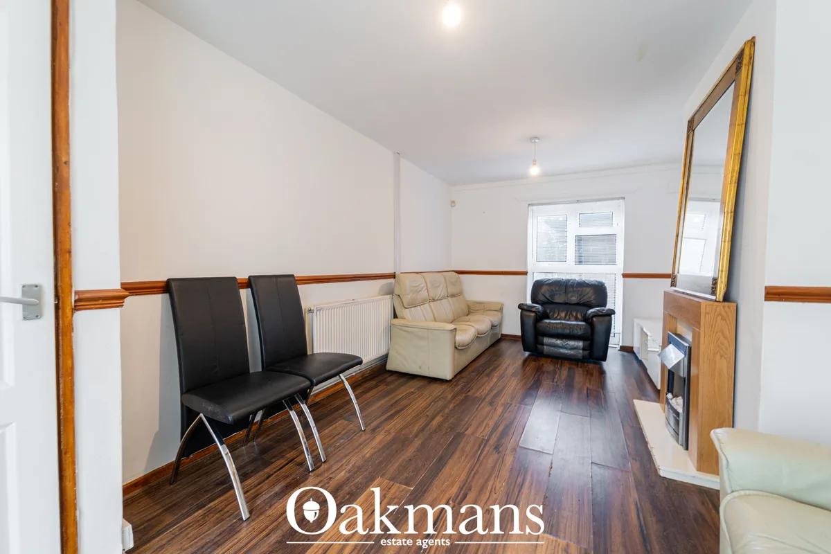 Spacious living room with dark wood flooring, mixed seating including black and cream leather chairs, recessed lighting,