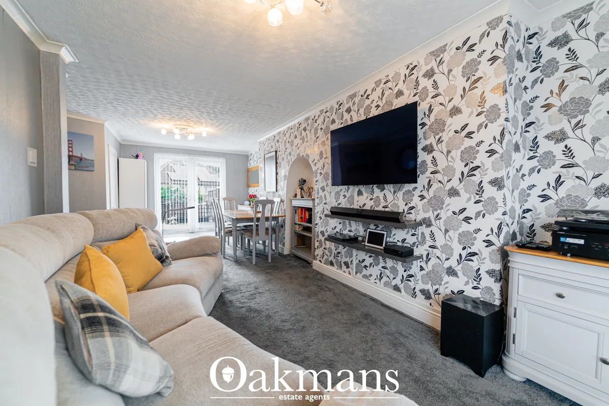 Spacious living room with beige sofa, patterned wallpaper feature wall, wall-mounted TV, fireplace, and open-plan access