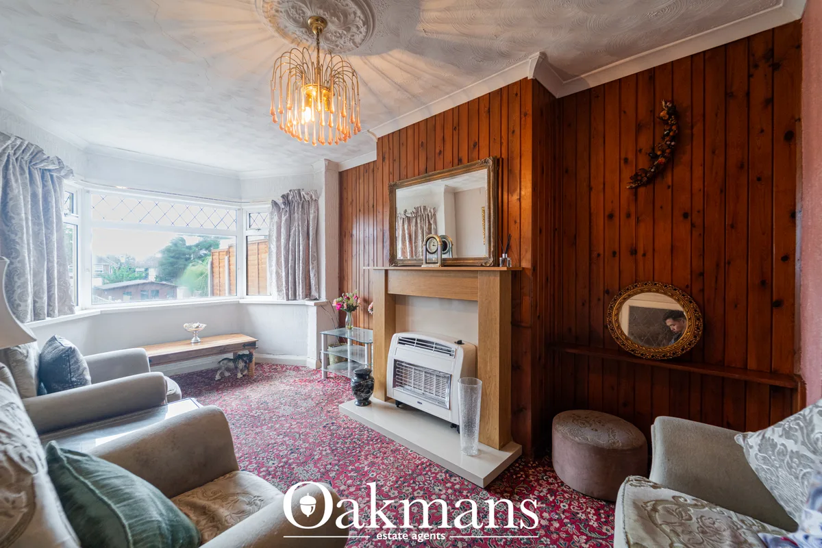 Elegant living room with wood panelling, fireplace, ornate ceiling rose, bay window with countryside views, and period f