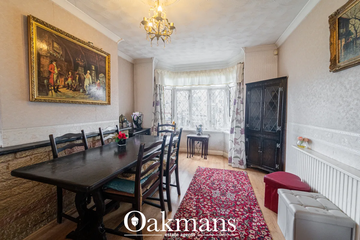 Formal dining room with black table, ladder-back chairs, bay windows with patterned curtains, gilt-framed oil painting, 