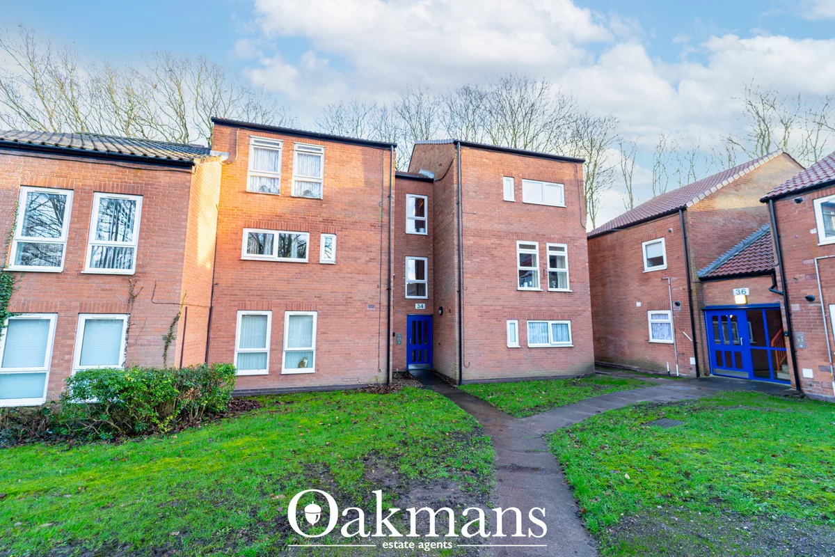 Red brick apartment building with blue entrance door, multiple windows, bare trees and green lawn to front