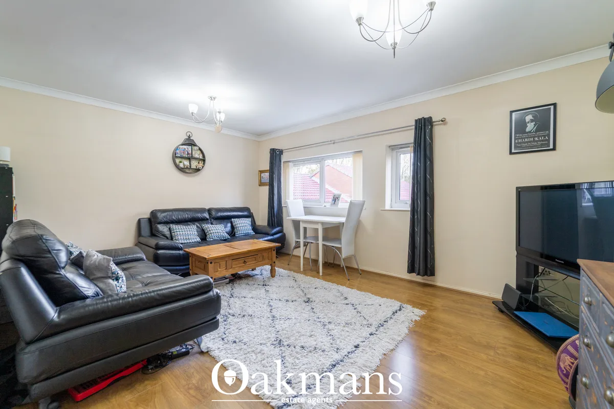 Spacious living room with black leather sofas, wooden coffee table, TV on stand, cream walls, wooden flooring and window