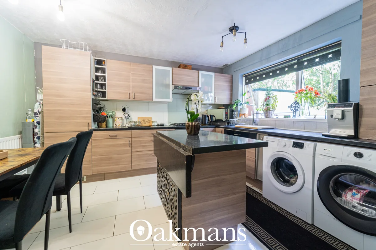 Modern fitted kitchen with light wood cabinetry, black granite island, stainless steel appliances, large window with gar