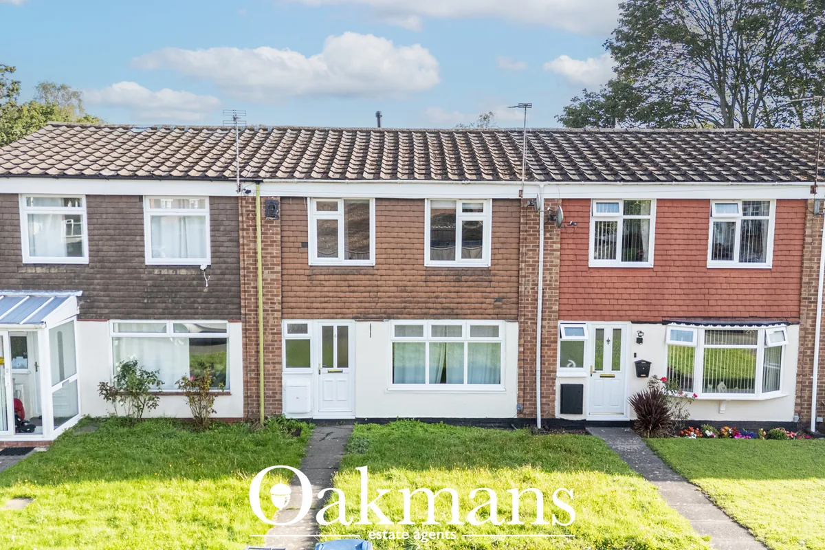 Front elevation of brick terraced houses with tile roof, white-framed windows, doors and small front gardens with lawn