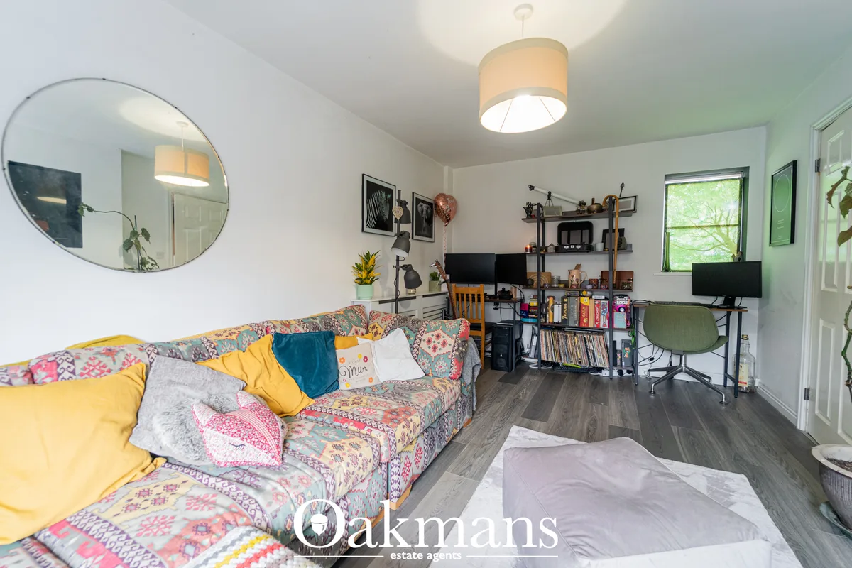 Bright open-plan living space with colourful patterned sofa, yellow and teal cushions, circular mirror, pendant lighting